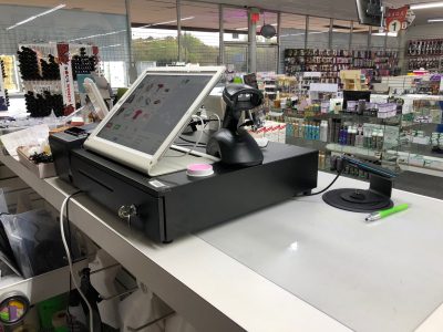 PUREJOIN beauty supply POS system installed at a retail checkout counter, featuring a touchscreen register, barcode scanner, and customer-facing display for streamlined sales transactions.