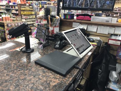 PUREJOIN beauty supply store POS system installed at a real retail checkout counter, featuring a touchscreen register, barcode scanner, and customer display for efficient sales transactions.